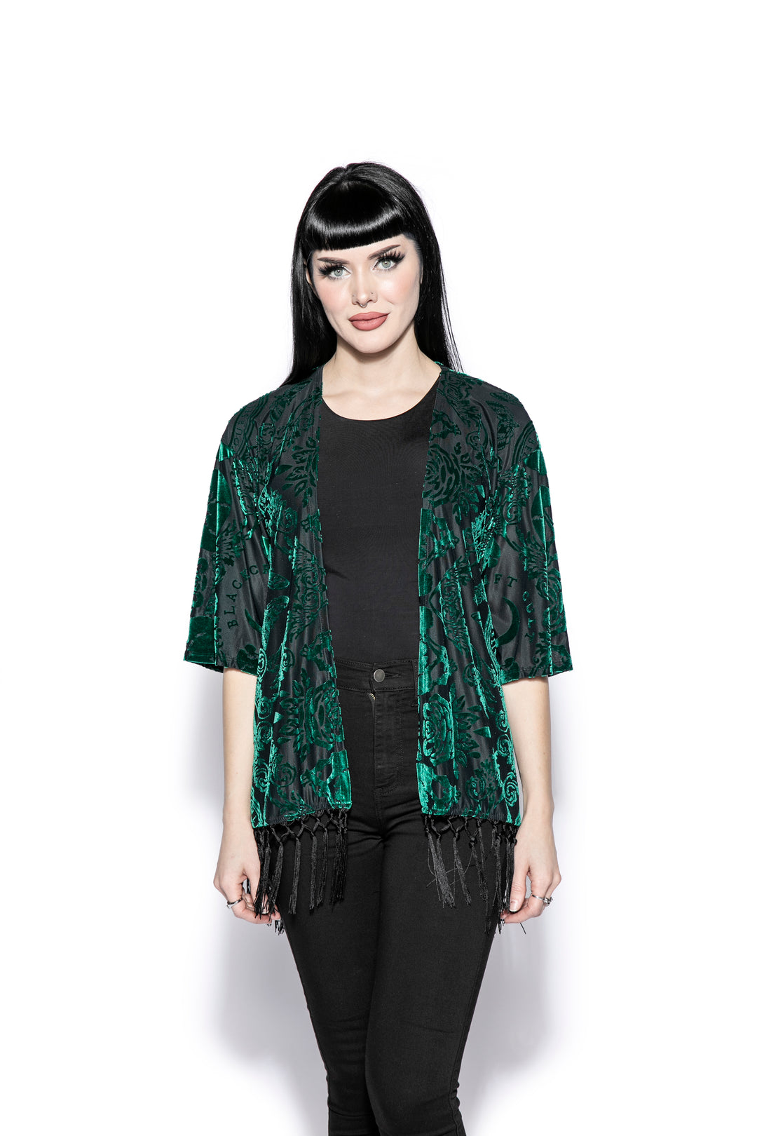 A gothic velvet kimono cover up with fringed trim, an open front, and kimono half length sleeves.