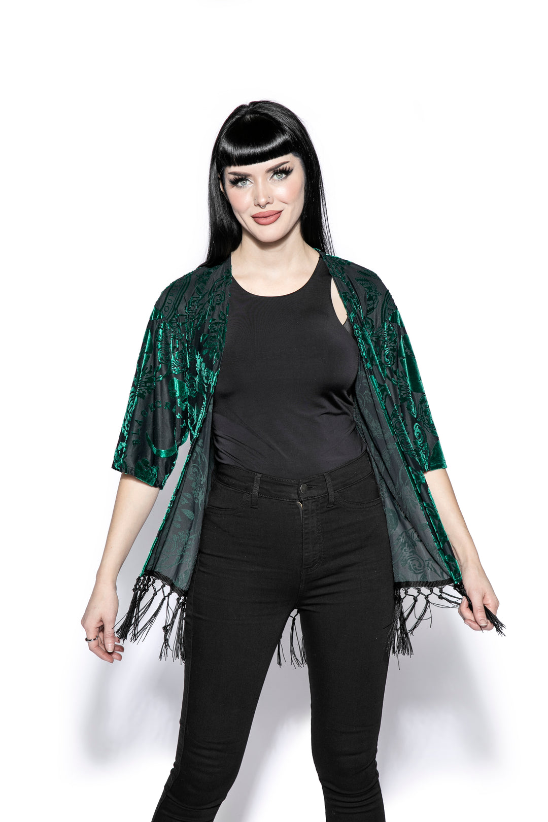 A gothic velvet kimono cover up with fringed trim, an open front, and kimono half length sleeves.