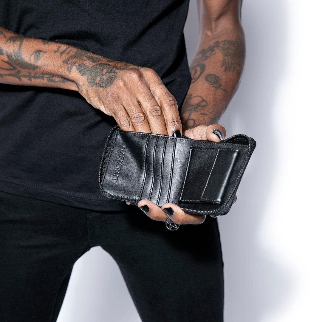 Small black faux leather zip around wallet with black hardware. 