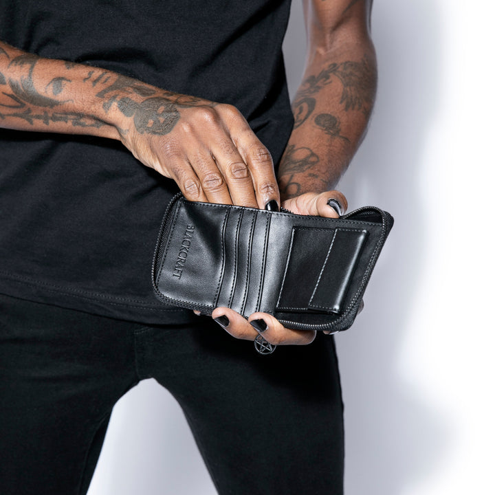 Small black faux leather zip around wallet with black hardware. 
