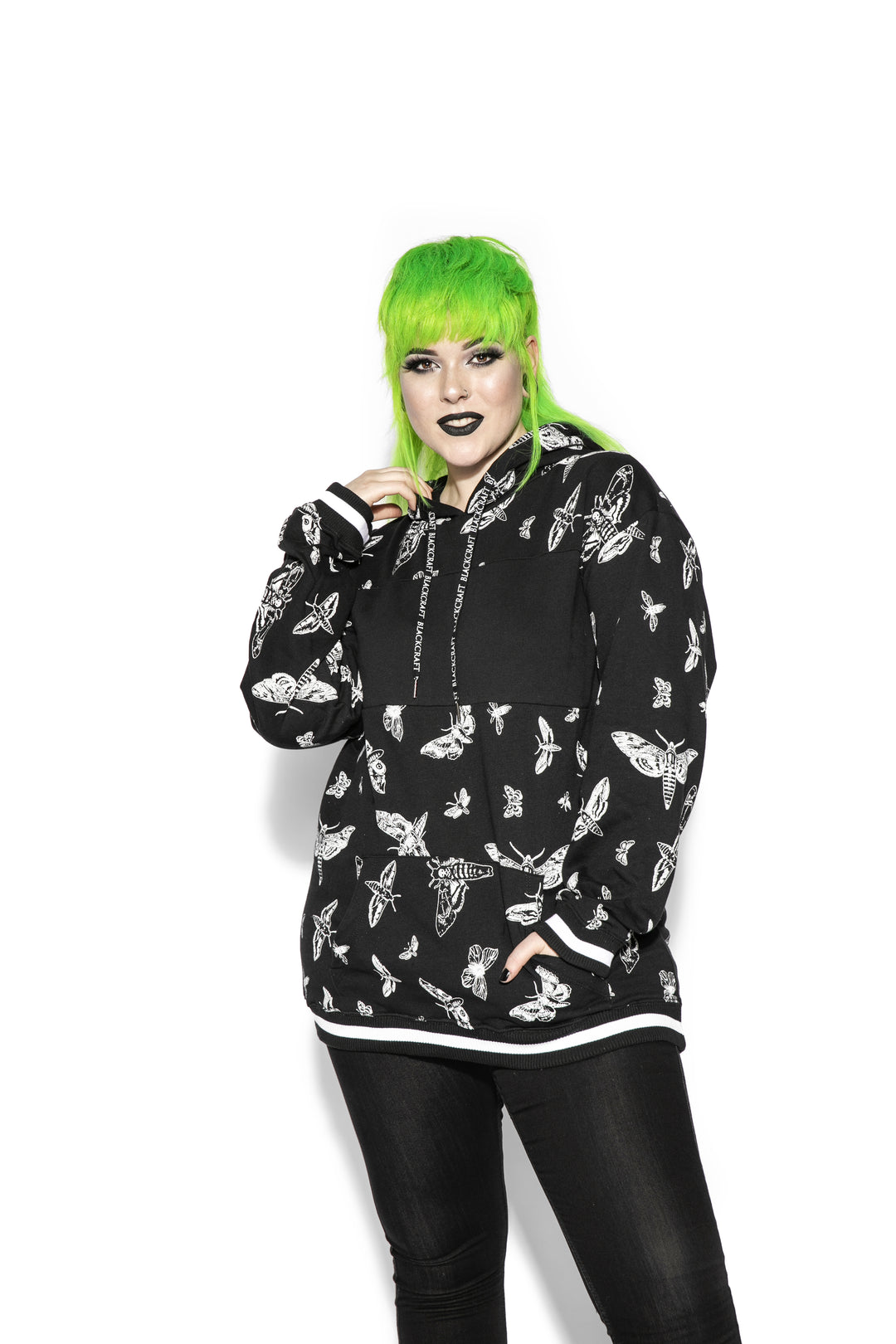 A model wearing a black and white pullover hoodie with custom Blackcraft moth artwork