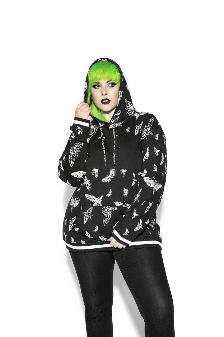 A model wearing a black and white pullover hoodie with custom Blackcraft moth artwork