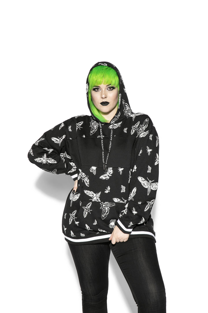 A model wearing a black and white pullover hoodie with custom Blackcraft moth artwork