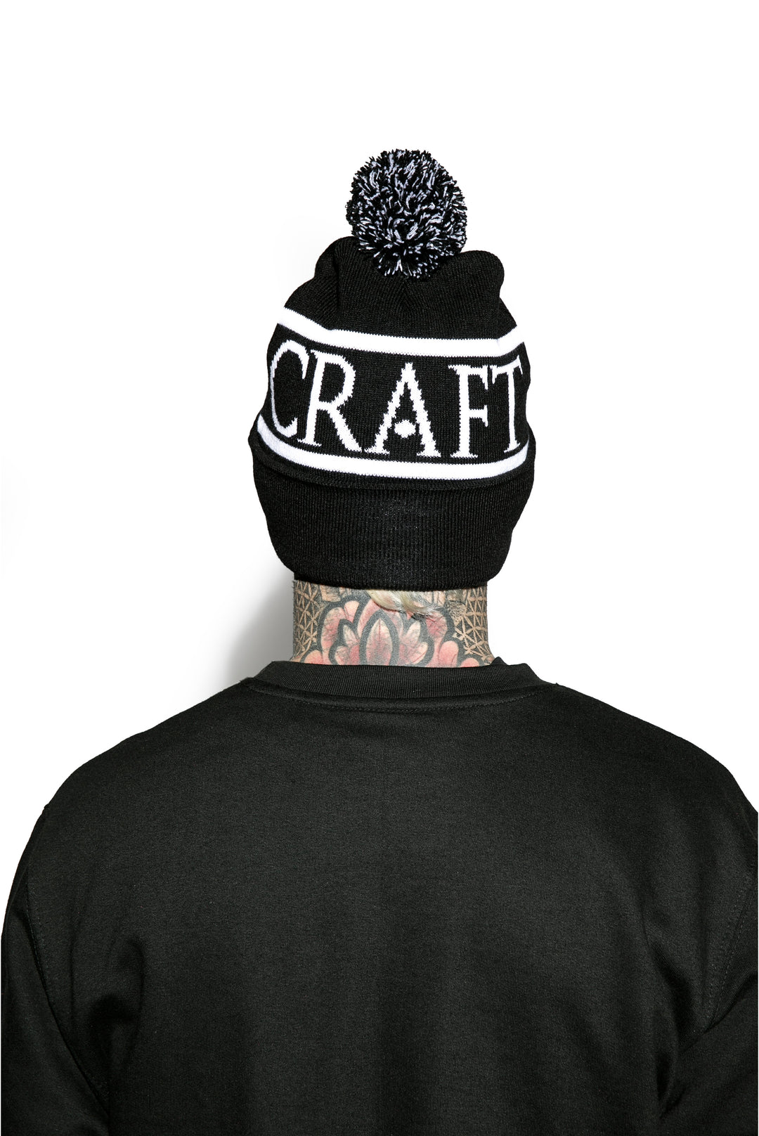 Model wearing a black bobble beanie with Blackcraft across the circumference.