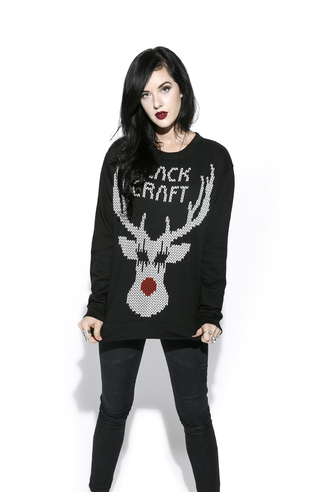 A black haired model wearing a black sweatshirt with the Blackcraft logo and a reindeer on the front and text on the back. 