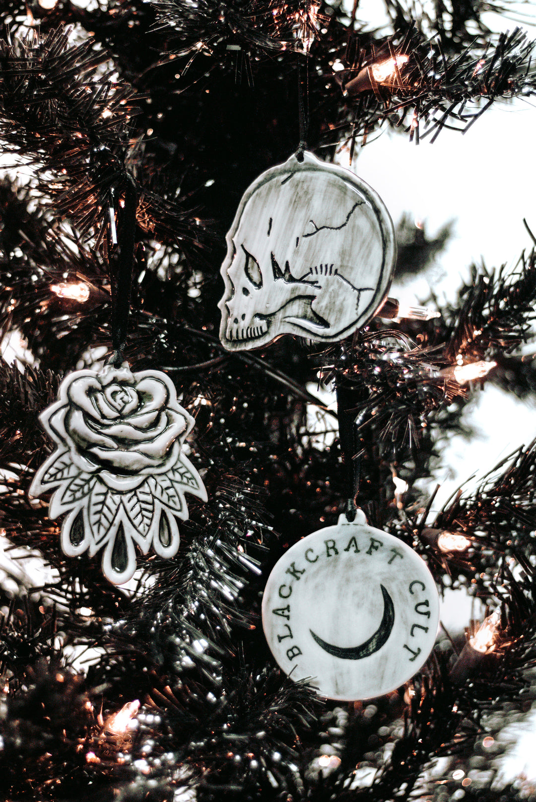 A three piece ceramic Christmas tree ornament set with skull, moon, and rose ornaments. From Blackcraft.