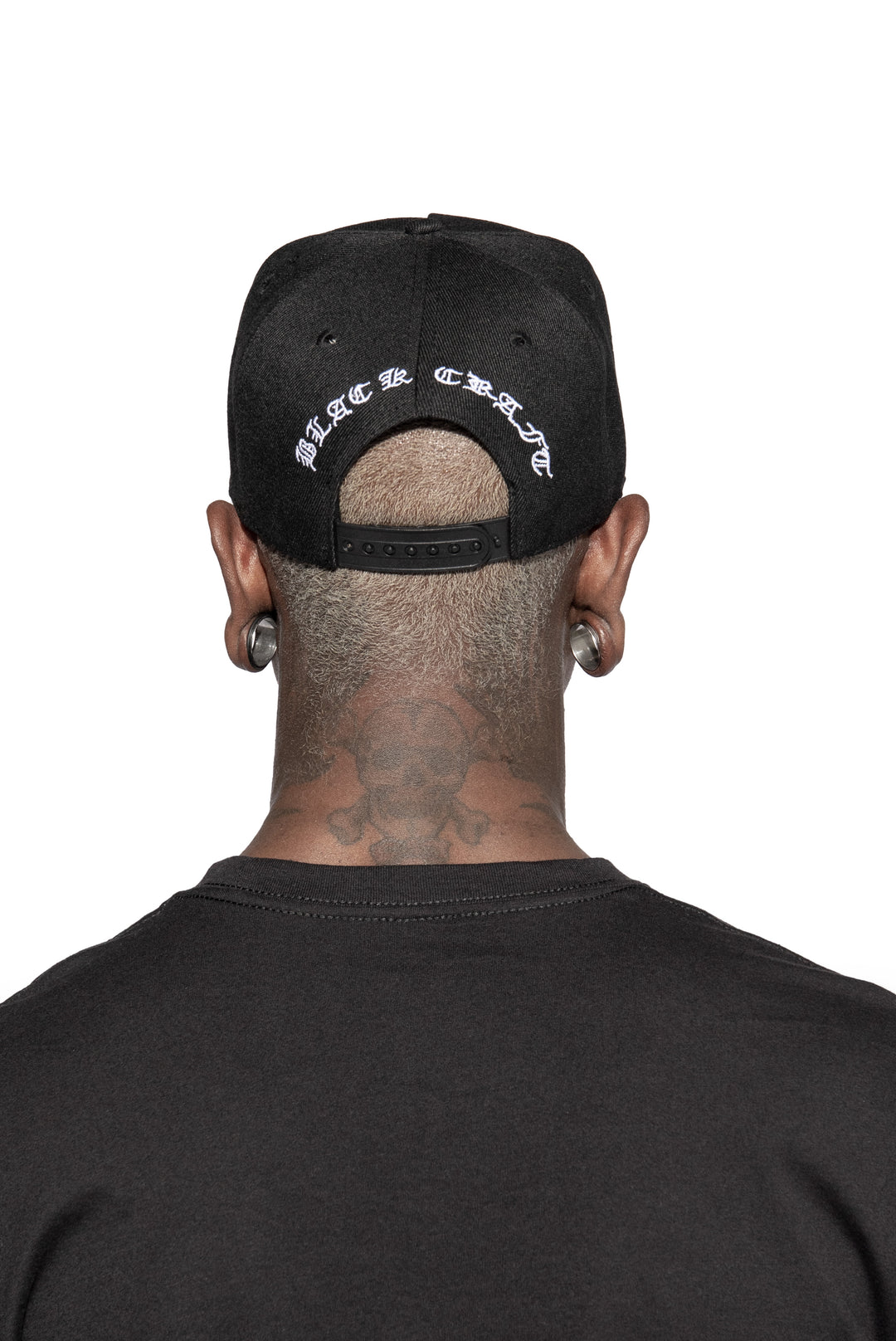 A model wearing a black snapback hat with white embroidered Satan is my Daddy on the front. 