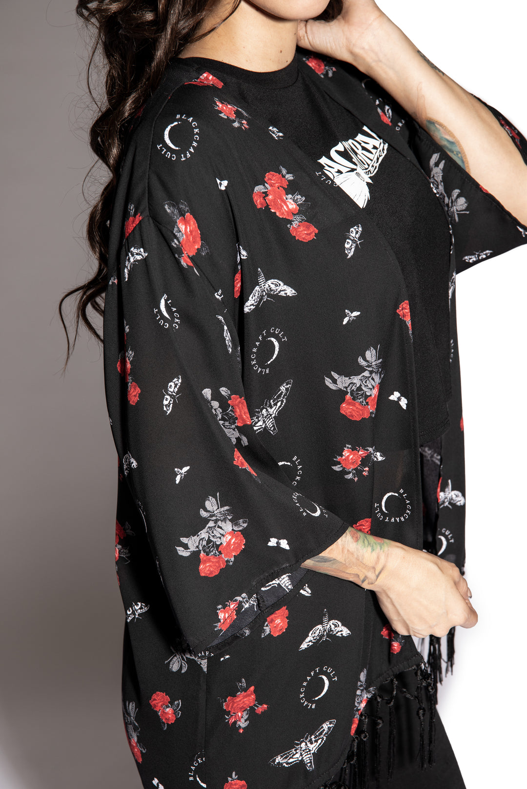 A gothic kimono cover up with fringed trim, and open front, and kimono half length sleeves.