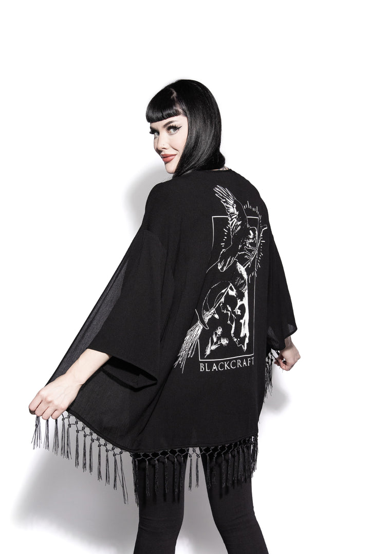 A gothic kimono cover up with fringed trim, and open front, and kimono half length sleeves.