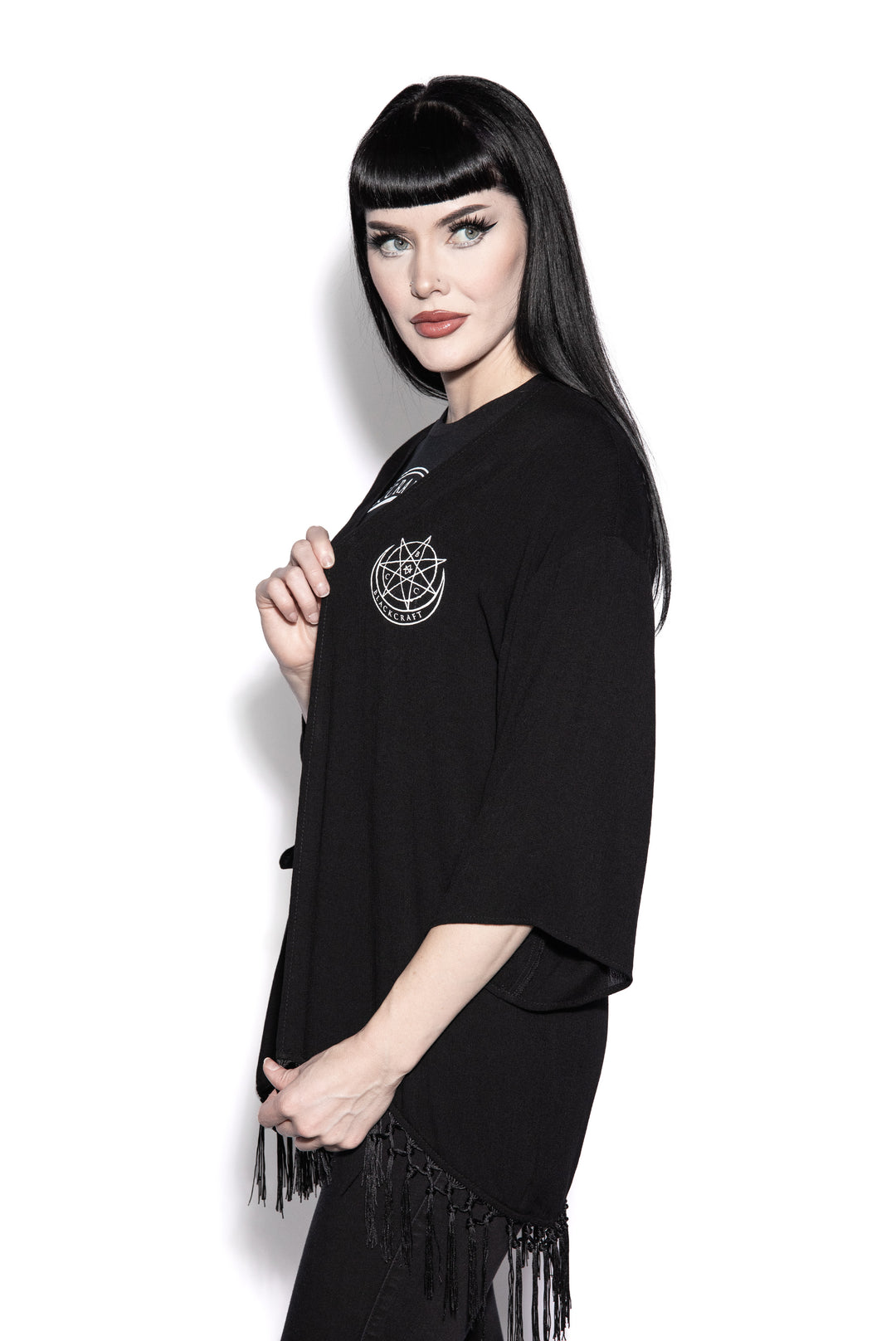 A gothic kimono cover up with fringed trim, and open front, and kimono half length sleeves.