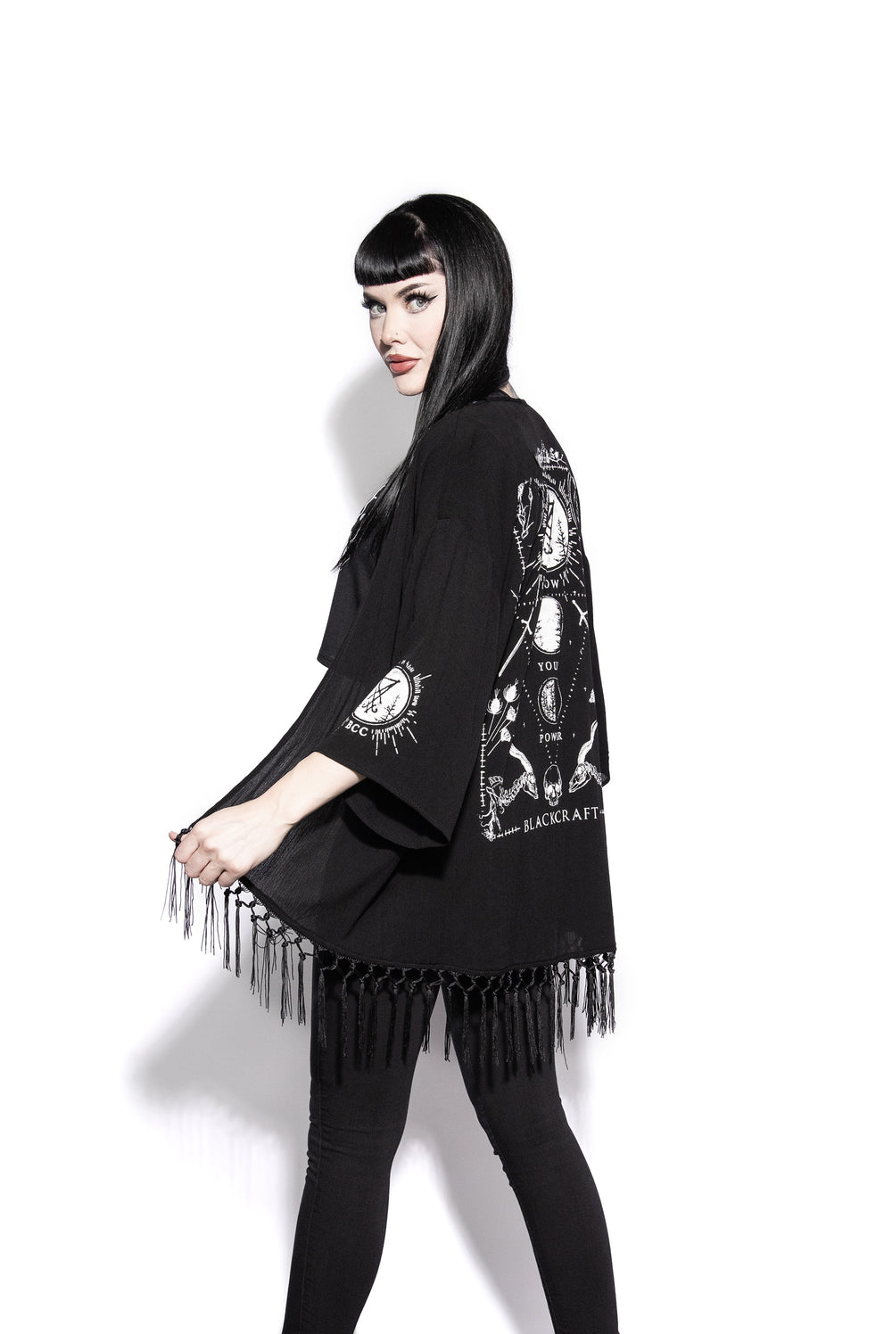 A gothic kimono cover up with fringed trim, and open front, and kimono half length sleeves.