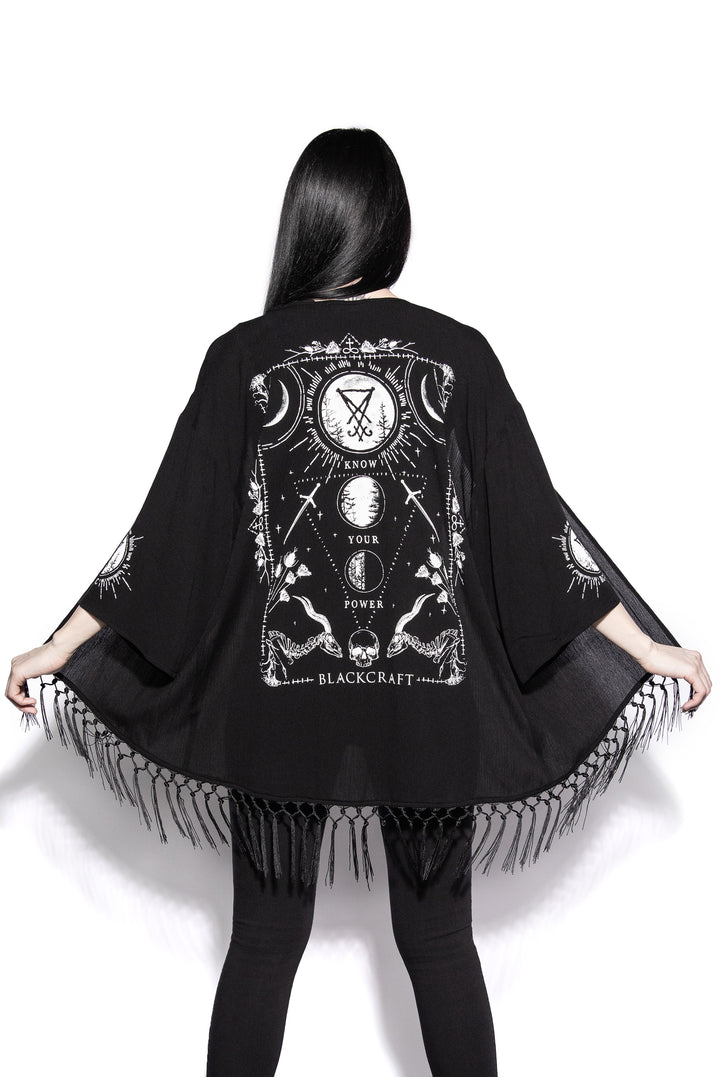 A gothic kimono cover up with fringed trim, and open front, and kimono half length sleeves.