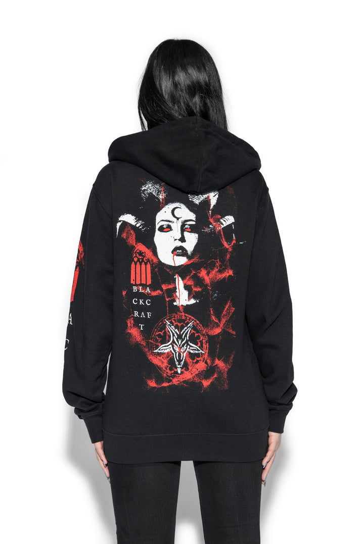 A brunette model wearing a classic black zip up hoodie with custom artwork on the front, back, and sleeves.