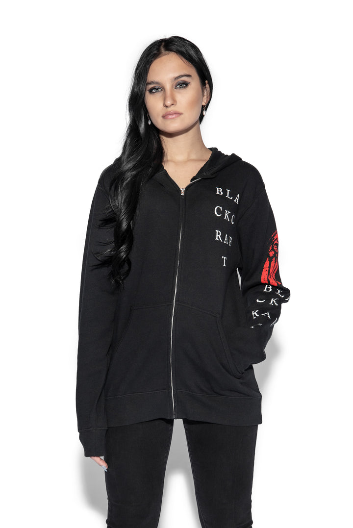 A brunette model wearing a classic black zip up hoodie with custom artwork on the front, back, and sleeves.